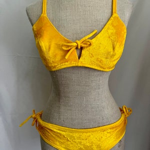 May include: A yellow velvet bikini with a bow detail on the top and tie sides on the bottom.