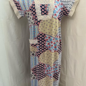 Puede incluir: Un vestido largo de patchwork con estampado floral en tonos azules, rosas y beige. El vestido tiene un ribete de encaje alrededor del escote y mangas cortas.