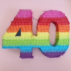 May include: A rainbow-coloured pinata shaped like the number 40. The pinata is made of tissue paper and has a triangular opening on the side.