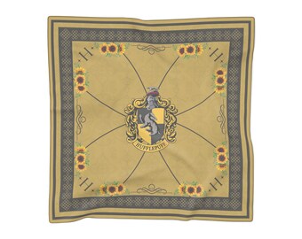 May include: A square scarf in mustard yellow featuring a central Hufflepuff crest with a badger, surrounded by sunflowers and the letter H in the corners. The design includes a dark grey geometric border and thin diagonal lines across the fabric.