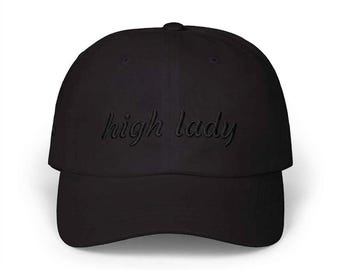 May include: A black baseball cap featuring the words high lady embroidered in a matching black thread across the front panel. The cap has a structured crown, a curved brim, and a button on top, presenting a monochromatic design throughout.