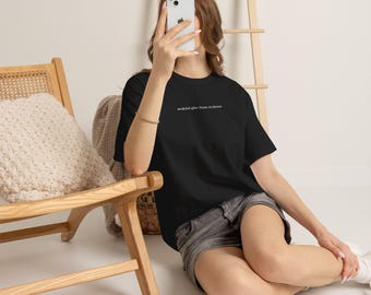 May include: A black short-sleeve t-shirt featuring the white text "modeled after Nesta Archeron" printed on the chest. The shirt has a crew neckline and a relaxed fit, paired with gray denim shorts. The design is simple and centered on the front.