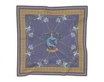 May include: A square scarf in muted blue featuring a central Ravenclaw crest with a black raven on a blue shield. The design includes light purple iris flowers, gold geometric border patterns, and the letter R in each corner on a blue background.