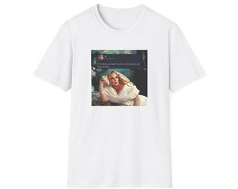 May include: A white short-sleeved t-shirt featuring a central graphic print of a person in a white dress holding a seashell to their ear. Above the figure is a dark social media post box containing the text: "It's all in your head" correct: unfortunately I am also in there.