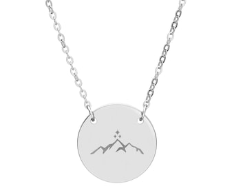 May include: A silver-toned necklace featuring a circular pendant suspended from a delicate link chain. The pendant is engraved with a mountain range silhouette topped by three small, four-pointed star shapes arranged in a vertical triangular pattern.