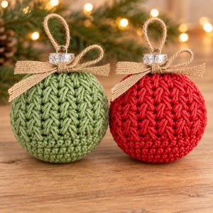 May include: Two spherical baubles, one sage green and one bright red, featuring a textured crochet knit pattern. Each bauble is topped with a silver-toned metal cap, a natural jute twine hanging loop, and a tied hessian ribbon bow.