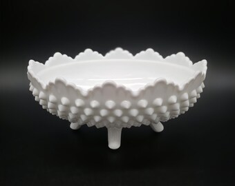 Op de afbeelding: Een witte melkglazen kom met een hobnail-textuur aan de buitenkant en een geschulpte rand. De kom wordt ondersteund door drie kleine, stevige voetjes, wat zorgt voor een verhoogd profiel. Het glasoppervlak is overal glad en opaak.