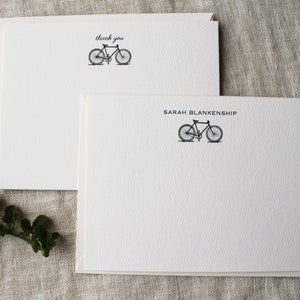 May include: Two white blank note cards with a black bicycle illustration. The top card says "thank you" and the bottom card says "SARAH BLANKENSHIP".