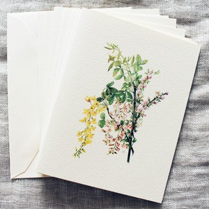 May include: A stack of blank white cards with a watercolor illustration of pink, yellow, and green flowers on the top card.
