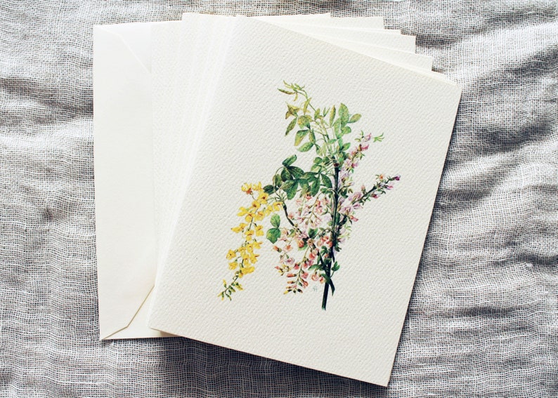 May include: A stack of blank white cards with a watercolor illustration of pink, yellow, and green flowers on the top card.