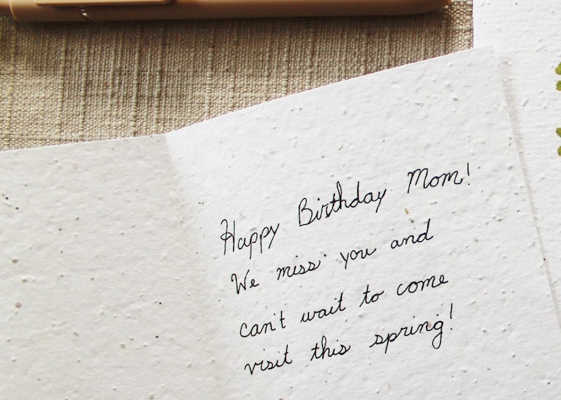 May include: A handwritten birthday card with the text "Happy Birthday Mom! We miss you and can't wait to come visit this spring!"
