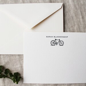 May include: White stationery card with a black bicycle illustration and the text "SARAH BLANKENSHIP" printed in black.