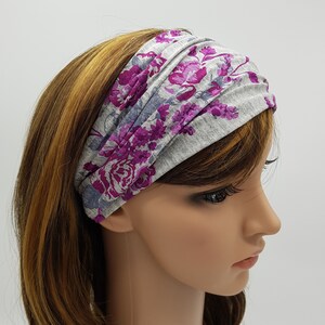 May include: A gray headband with a vibrant floral pattern in shades of purple and pink. The fabric is soft and gathered, creating a comfortable and stylish accessory. This headband is perfect for adding a pop of color to any outfit.