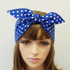 Peut inclure: Un bandeau bleu avec des pois blancs, noué en nœud. Le tissu est enroulé autour de la tête et noué sur le dessus, créant un style rétro. Le bandeau est bleu vif avec des pois blancs espacés.