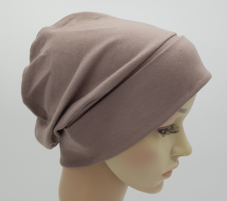 May include: A soft, brown beanie hat made of jersey knit fabric. The hat has a slouchy fit and a fold-over brim.