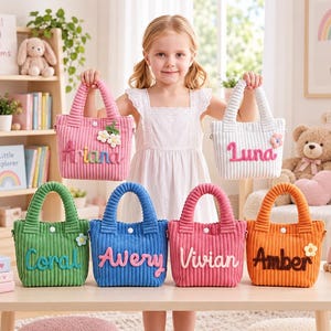 May include: A collection of six small corduroy tote bags in pink, white, green, blue, magenta, and orange. Each bag features a white snap closure, a small flower accent, and a personalized name in raised, colorful, felt-like script lettering.