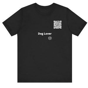 May include: A black short-sleeved t-shirt featuring the white text Dog Lover, a white QR code, and a small white circular logo with the letter M in the center, all positioned on the upper right chest area of the garment.