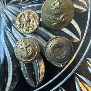以下が含まれることがあります： ミリタリースタイルのエンボス加工が施された4つの円形真鍮ボタン。1つは王冠と鷲、もう1つは錨の上に止まる鷲、残りの2つは錨のデザインで、そのうち1つは王冠が上に配置されています。