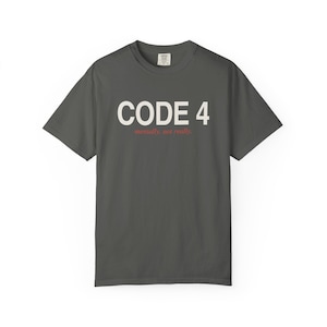 May include: A charcoal gray short-sleeve t-shirt featuring the white text CODE 4 printed in a bold sans-serif font, with the smaller red text mentally, not really. positioned directly underneath the main graphic on the chest area.