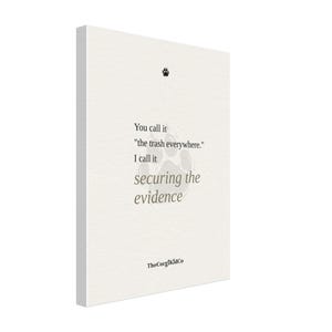 May include: A rectangular white canvas wall art piece featuring a small black paw print icon at the top. The text reads: You call it "the trash everywhere." I call it securing the evidence. A large, faint paw print is centered behind the text.