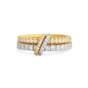 May include: A stack of two eternity bands, one in yellow gold and one in white metal, both featuring a continuous row of round brilliant-cut white diamonds. A third, smaller diamond-encrusted band is positioned diagonally across the two rings.