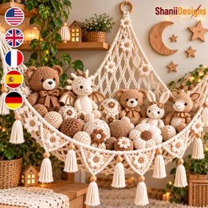 Op de afbeelding: Een crèmekleurige macramé speelgoedhangmat met bloemaccenten en hangende kwastjes, gevuld met diverse gehaakte knuffels waaronder beren, een draak en een konijn, samen met verschillende gehaakte ballen in bruin- en wittinten.