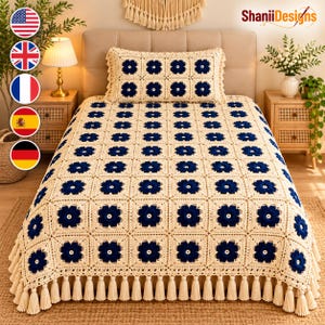 May include: A cream-colored crochet bedspread and matching rectangular pillow featuring a repeating pattern of dark navy blue floral motifs. The bedspread is finished with a decorative fringe of cream tassels along the bottom edge.