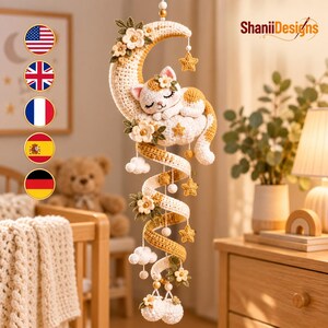 Puede incluir: Un móvil de ganchillo colgante que presenta un gato durmiendo sobre una luna creciente de color crema. El diseño incluye estrellas de ganchillo amarillas y blancas, pequeñas nubes blancas y detalles florales en tonos crema y verde, suspendidos en espiral.