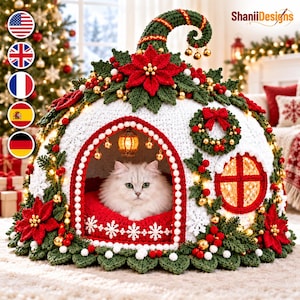 May include: A white crocheted pet bed shaped like a festive dome with a curled top, decorated with red poinsettias, green leaves, gold beads, and a small wreath. A white cat sits inside on a red cushion with snowflake patterns and a hanging lantern.