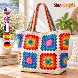 May include: A crochet tote bag featuring a cream-colored base with multiple square motifs in vibrant rainbow colors. The bag includes two matching handles with a rainbow-striped pattern. The text ShaniiDesigns is visible in the upper right corner.