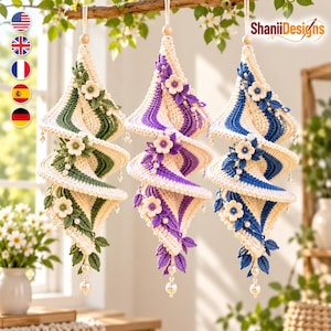 May include: Three hanging spiral ornaments made of cream-colored crochet yarn, each featuring a different accent color of green, purple, or blue. Each ornament is decorated with small crocheted flowers, leaves, and white beads.