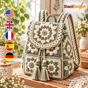 May include: A crochet backpack featuring a sage green and cream floral motif made of joined square panels. The bag has a flap with a large central flower, braided shoulder straps, and two long tassels hanging from the drawstring closure.