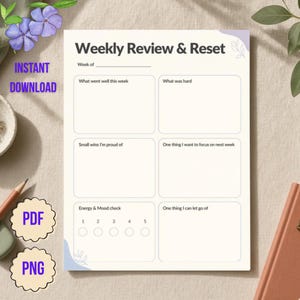 Op de afbeelding: Een Weekly Review & Reset plannerpagina met een crèmekleurige achtergrond en lichtpaarse accenten in de hoeken. De lay-out bevat secties voor What went well this week, What was hard, Small wins, Focus for next week, Energy & Mood check en Let go of.