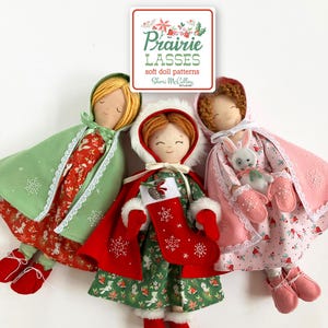 May include: Three handmade soft dolls with smiling faces, wearing capes and dresses. One doll has a green cape and red dress, another has a red cape and green dress, and the third has a pink cape and dress. The dolls are part of the "Prairie Lasses" soft doll patterns.