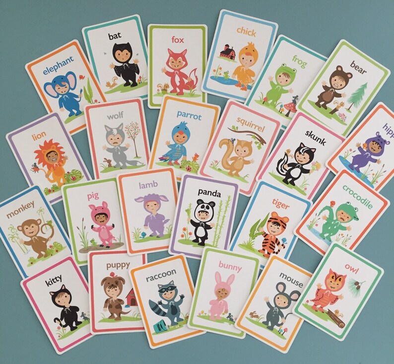 May include: A set of 24 colorful flashcards featuring various animals dressed in costumes. Each card has a different animal name printed on it, such as elephant, bat, fox, chick, frog, bear, lion, wolf, parrot, squirrel, skunk, hippo, crocodile, monkey, pig, lamb, kitty, puppy, raccoon, panda, tiger, bunny, mouse, and owl.