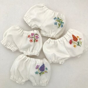 May include: Four white cotton bloomers with embroidered floral designs. Each bloomer features a different colourful floral pattern.
