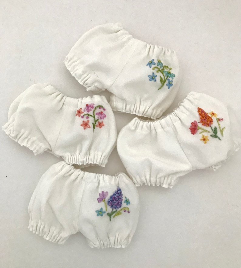 May include: Four white cotton bloomers with embroidered floral designs. Each bloomer features a different colourful floral pattern.