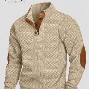 May include: A beige long-sleeve jumper featuring a textured diamond and cable knit pattern, a mock neck collar with a four-button placket, brown faux leather trim along the placket, and matching brown faux leather elbow patches on each sleeve.