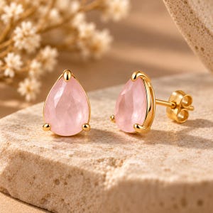 Peut inclure: Une paire de boucles d'oreilles à clous en or avec des pierres précieuses rose clair en forme de poire à facettes. Chaque pierre est fixée par trois griffes en or, et les boucles d'oreilles incluent des fermoirs à tige en or.