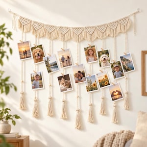 May include: A cream-colored macrame wall hanging featuring a series of triangular woven patterns along the top edge. Multiple vertical cords hang down, each adorned with small wooden beads and finished with a tassel, holding various photographs.