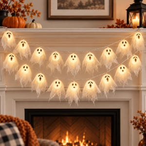 May include: A string of LED fairy lights featuring multiple white fabric ghost covers with black printed facial expressions. Each ghost is illuminated from within, creating a warm glow. The light strand is draped in two horizontal rows.