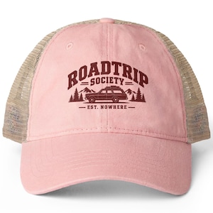 Peut inclure: Une casquette de type trucker rose clair avec un filet arrière beige. Le panneau avant présente un motif bordeaux représentant un break avec des bagages sur le toit, des sapins et des montagnes, avec le texte ROADTRIP SOCIETY EST. NOWHERE.
