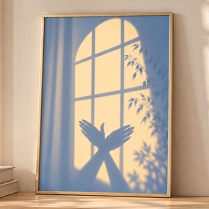May include: A rectangular wall art print in a thin gold frame featuring a blue and yellow graphic of a window with an arched top. The image displays the shadow of hands forming a bird shape, alongside the silhouette of leafy plant branches.