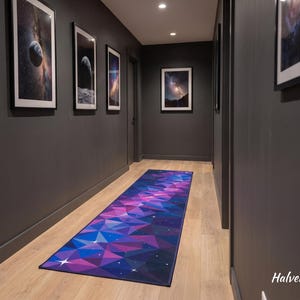 May include: A rectangular runner rug featuring a geometric pattern of triangles in shades of purple, blue, and pink with small white star-like accents. The rug is positioned on a light wood floor in a hallway with dark gray walls.