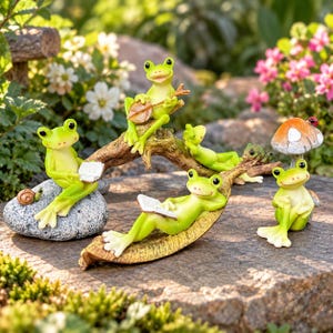May include: A set of five light green frog figurines in various poses, including one sitting on a grey stone with a book, one on a branch playing a banjo, one lounging on a leaf with a book, one resting on a branch, and one by a mushroom.