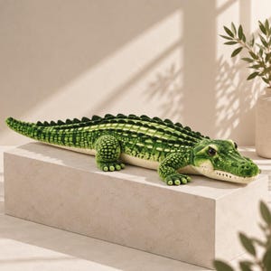May include: A plush crocodile toy featuring a vibrant green textured exterior with dark green scale patterns along the back and tail. The stuffed animal has a cream-coloured underbelly, four short legs with visible toes, and dark brown eyes.