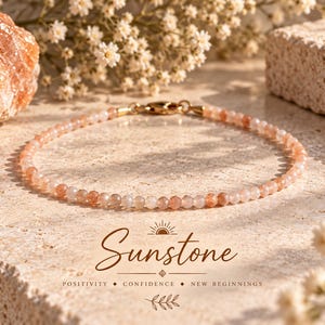 Può includere: Un braccialetto delicato composto da piccole perle di pietra del sole traslucide, sfaccettate, nei toni del pesca e dell'arancione. Il braccialetto presenta una chiusura a moschettone in metallo dorato. Sotto il braccialetto, il testo recita Sunstone, Positivity, Confidence, New Beginnings.