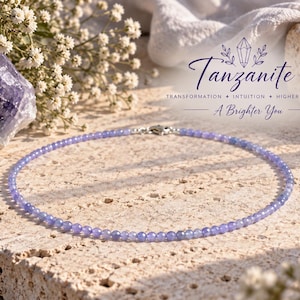 Può includere: Una collana delicata con piccole perline rotonde di tanzanite color viola chiaro e una chiusura in metallo color argento. Il testo nell'immagine recita: Tanzanite, Transformation, Intuition, Higher Purpose, A Brighter You.
