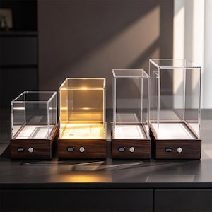 May include: Four rectangular display cases with clear acrylic covers and dark wood-grain bases. Each base features a silver circular button and a USB-C charging port. One case is illuminated with a warm internal light, while the others are unlit.