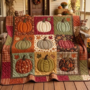 May include: A patchwork quilt featuring nine square panels, each displaying a unique fabric pumpkin design in shades of orange, cream, green, and brown. The quilt is bordered by a quilted plaid fabric pattern in warm autumn colors.
